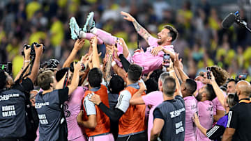 Inter Miami CF players toss a joyous Lionel Messi into the air while, in the background, yellow-clad Nashville SC fans head for the exits at Geodis Park after the Herons won a penalty-kick shootout to claim the 2023 Leagues Cup.