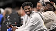 Jan 14, 2025; Dallas, Texas, USA; Colorado Buffaloes quarterback Shedeur Sanders laughs as he watches the game between the Dallas Mavericks and the Denver Nuggets during the second half at the American Airlines Center. Mandatory Credit: Jerome Miron-Imagn Images