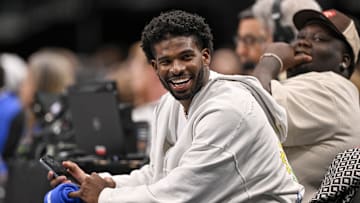 Jan 14, 2025; Dallas, Texas, USA; Colorado Buffaloes quarterback Shedeur Sanders laughs as he watches the game between the Dallas Mavericks and the Denver Nuggets during the second half at the American Airlines Center. Mandatory Credit: Jerome Miron-Imagn Images