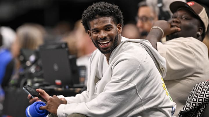 Jan 14, 2025; Dallas, Texas, USA; Colorado Buffaloes quarterback Shedeur Sanders laughs as he watches the game between the Dallas Mavericks and the Denver Nuggets during the second half at the American Airlines Center. Mandatory Credit: Jerome Miron-Imagn Images