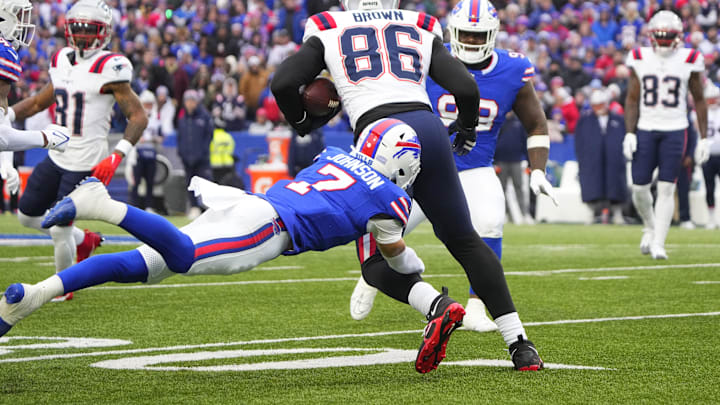 Dec 31, 2023; Orchard Park, New York, USA; New England Patriots tight end Pharaoh Brown (86) runs with the ball after making a catch and is tackled by Buffalo Bills cornerback Taron Johnson (7) during the first half at Highmark Stadium.