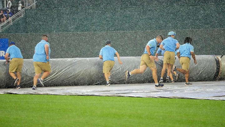 Jun 12, 2025; Kansas City, Missouri, USA; The Kansas City Royals grounds crew scrambles to spread the tarp over the field during the sixth inning rain delay of the game against the New York Yankees at Kauffman Stadium. Mandatory Credit: Denny Medley-Imagn Images