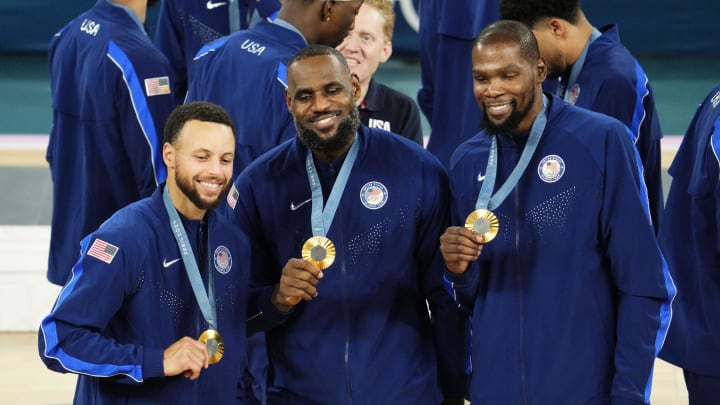 Aug 10, 2024; Paris, France; United States shooting guard Stephen Curry (4) and guard LeBron James (6) and guard Kevin Durant (7) celebrate with their gold medals on the podium after defeating France in the men's basketball gold medal game during the Paris 2024 Olympic Summer Games at Accor Arena. Mandatory Credit: Rob Schumacher-USA TODAY Sports