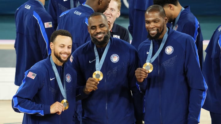 Aug 10, 2024; Paris, France; United States shooting guard Stephen Curry (4) and guard LeBron James (6) and guard Kevin Durant (7) celebrate with their gold medals on the podium after defeating France in the men's basketball gold medal game during the Paris 2024 Olympic Summer Games at Accor Arena. Mandatory Credit: Rob Schumacher-USA TODAY Sports