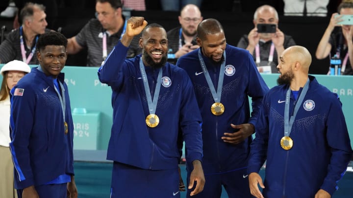 The United States' Anthony Edwards (5), LeBron James (6),  Kevin Durant (7) and Derrick White (8) celebrate with their gold medals on the podium after defeating France in the men's basketball gold-medal game during the Paris Olympics at Accor Arena in Paris on Aug. 10, 2024. 