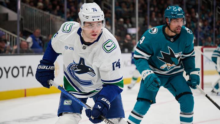 Nov 2, 2024; San Jose, California, USA; Vancouver Canucks left wing Jake DeBrusk (74) skates against San Jose Sharks defenseman Jan Rutta (84) during the first period at SAP Center at San Jose. Mandatory Credit: Robert Edwards-Imagn Images