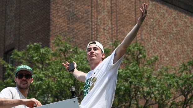 Celtics guard Payton Pritchard holds his arms out towards the crowd in celebration during the 2024 NBA championship parade.