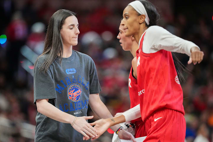 Indiana Fever guard Caitlin Clark high-flves forward DeWanna Bonner during a game against the Connecticut Sun.