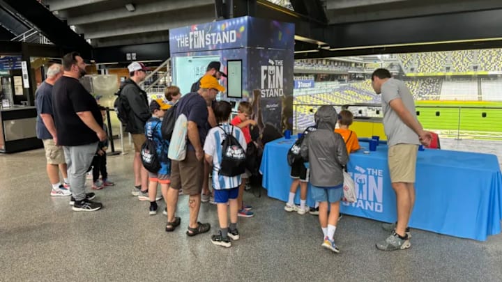 Fans gather around a "Fan Stand", a sports card vending machine Fans gather around a "Fan Stand", a sports card vending machine