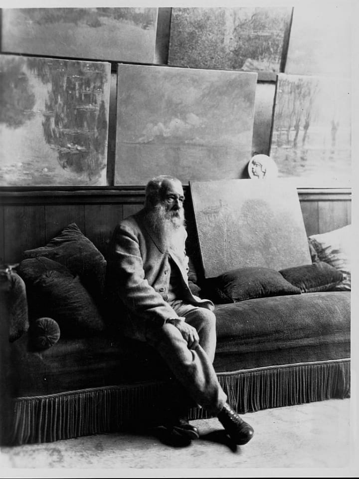Claude Monet sitting on a couch surrounded by paintings