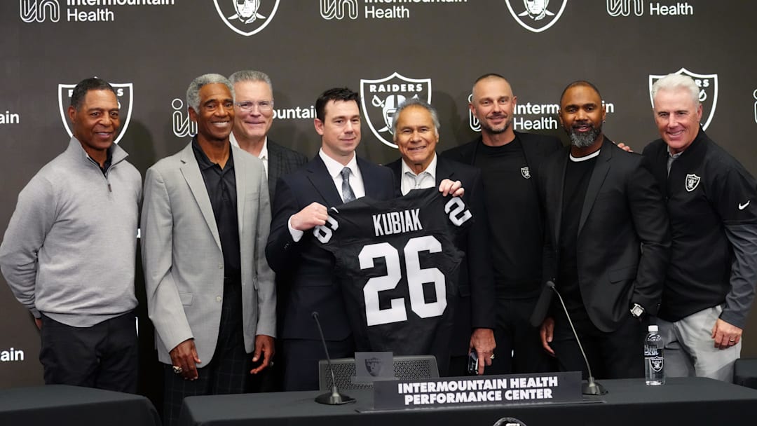 Feb 10, 2026; Henderson, NV, USA; Las Vegas Raiders coach Klint Kubiak (center) poses at introductory press conference at Intermountain Health Performance Center. From left: Marcus Allen, Mike Haynes, Howie Long, Kubiak, general manager John Spyktek, Charles Woodson and Rich Gannon. Mandatory Credit: Kirby Lee-Imagn Images