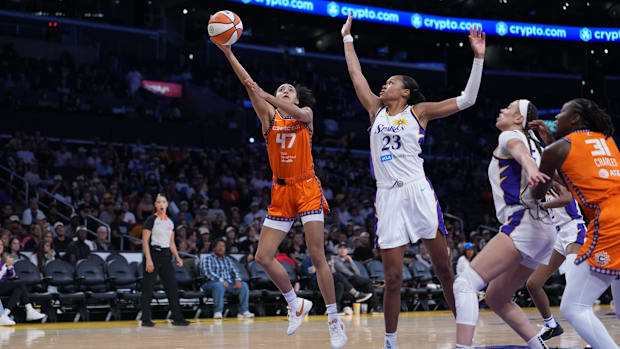 Connecticut Sun guard Leila Lacan goes up to try and shoot a layup, wearing an orange jersey with a black border.