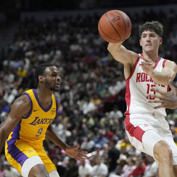 Jul 12, 2024; Las Vegas, NV, USA;  Houston Rockets guard Reed Sheppard (15) passes the ball between Los Angeles Lakers guard Bronny James (9) and forward Maxwell Lewis (21) during the first half at the Thomas & Mack Center. Mandatory Credit: Lucas Peltier-USA TODAY Sports