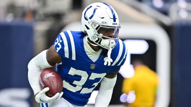 Colts cornerback Dallis Flowers (blue jersey; white trim/numbers) runs with the brown football before the game. 