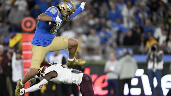 Nov 11, 2023; Pasadena, California, USA;  UCLA Bruins tight end Moliki Matavao (88) leaps over Arizona State Sun Devils defensive back Shamari Simmons (7) after making a catch during the first half at the Rose Bowl. Mandatory Credit: Alex Gallardo-USA TODAY Sports