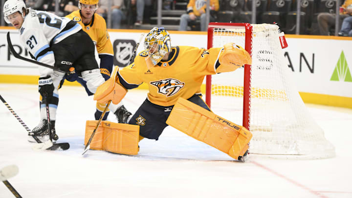 Apr 14, 2025; Nashville, Tennessee, USA;  Nashville Predators goaltender Juuse Saros (74) blocks the shot of Utah Hockey Club center Barrett Hayton (27) during the second period at Bridgestone Arena. Mandatory Credit: Steve Roberts-Imagn Images