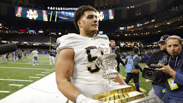 Jan 2, 2025; New Orleans, LA, USA; Notre Dame Fighting Irish defensive lineman Howard Cross III (56) carries the trophy off the field after defeating the Georgia Bulldogs at Caesars Superdome. Mandatory Credit: Amber Searls-Imagn Images