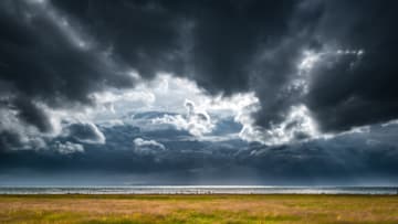 A massive thunderstorm turns the sky dark over a field in Sweden.
