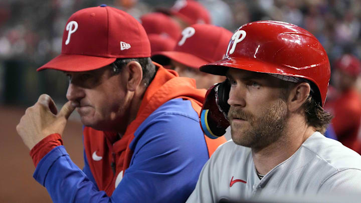 Philadelphia Phillies manager Rob Thomson (left) and first baseman Bryce Harper (right) look on from the dugout during a game against the Arizona Diamondbacks in June of 2023. 