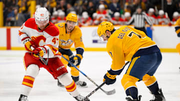 Dec 10, 2024; Nashville, Tennessee, USA;  Calgary Flames center Connor Zary (47) and Nashville Predators defenseman Marc Del Gaizo (7) battle for the puck during the second period at Bridgestone Arena. Mandatory Credit: Steve Roberts-Imagn Images