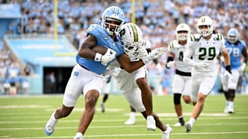 Sep 7, 2024; Chapel Hill, North Carolina, USA; North Carolina Tar Heels wide receiver Christian Hamilton (7) with the ball as Charlotte 49ers defensive back Al-Ma'hi Ali (0) defends in the second quarter at Kenan Memorial Stadium. Mandatory Credit: Bob Donnan-Imagn Images