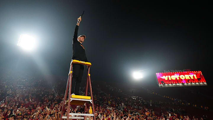 Nov 29, 2025; Los Angeles, California, USA; Southern California Trojans head coach Lincoln Riley leads the Spirit of Troy marching band in a rendition of Tribute to Troy after teh game against the UCLA Bruins at United Airlines Field at Los Angeles Memorial Coliseum. Mandatory Credit: Kirby Lee-Imagn Images