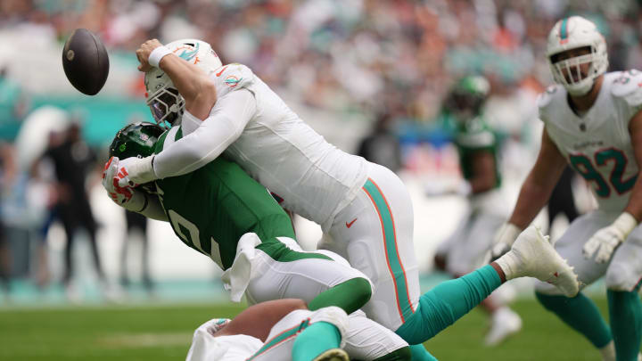 Miami Dolphins linebacker Bradley Chubb, top, and defensive tackle Christian Wilkins, bottom, hit New York Jets quarterback Zach Wilson (2), causing a fumble during the first half of an NFL game at Hard Rock Stadium in Miami Gardens, Dec. 17, 2023.