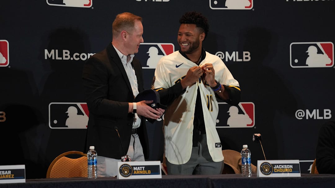 Dec 4, 2023; Nashville, TN, USA; Milwaukee Brewers general manager Matt Arnold presents Jackson Chourio with a team uniform and hat during the MLB 2023 Winter Meetings. Mandatory Credit: Kyle Schwab-Imagn Images