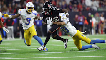 Jan 11, 2025; Houston, Texas, USA; Houston Texans wide receiver Diontae Johnson (82) runs the ball after a reception against Los Angeles Chargers defensive back Deane Leonard (33) and safety Derwin Jarnes Jr. (3) during the third quarter in an AFC wild card game at NRG Stadium.