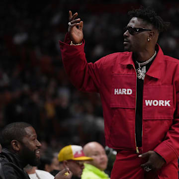 Mar 26, 2022; Miami, Florida, USA; Former NFL player Antonio Brown gestures to the fans while standing in from t of former professional boxer Floyd Mayweather Jr. during the second half between the Miami Heat and the Brooklyn Nets at FTX Arena. Mandatory Credit: Jasen Vinlove-Imagn Images