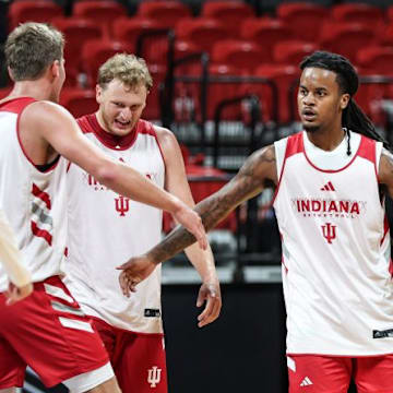 Indiana basketball guard Lamar Wilkerson high-fives teammate Trent Sisley, standing between Tucker DeVries and Ian Stephens.