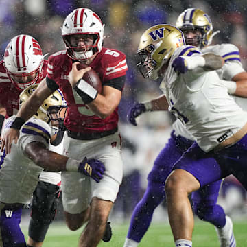 Nov 8, 2025; Madison, Wisconsin, USA;  Wisconsin Badgers quarterback Carter Smith (5) rushes with the football between Washington Huskies linebacker Deven Bryant (17) and defensive lineman Ta'ita'i Uiagalelei (11) during the third quarter at Camp Randall Stadium. Mandatory Credit: Jeff Hanisch-Imagn Images