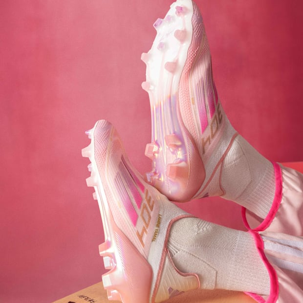 Pink adidas boots on a desk.