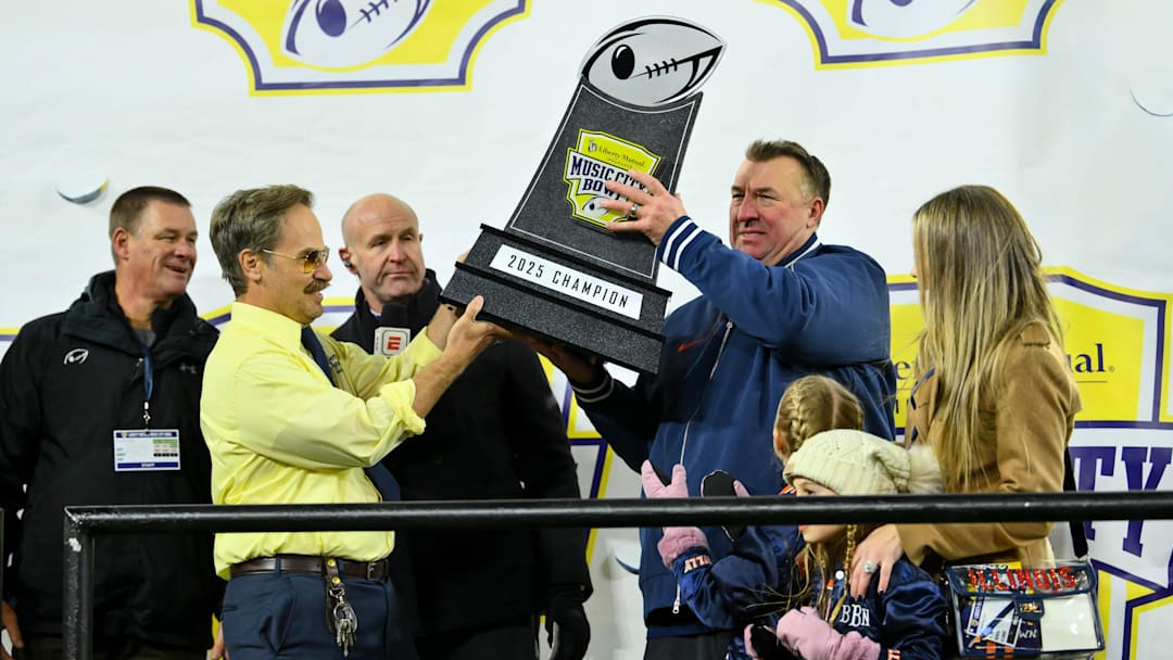 Dec 30, 2025; Nashville, TN, USA;  Illinois Fighting Illini head coach Bret Bielema hoist the trophy with Doug from Liberty Mutual against the Tennessee Volunteers during the second half at Nissan Stadium. Mandatory Credit: Steve Roberts-Imagn Images