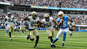 Aug 10, 2025; Inglewood, California, USA; Los Angeles Chargers quarterback Trey Lance (5) carries the ball against New Orleans Saints cornerback Quincy Riley (29) and linebacker D'Marco Jackson (52) in the first half at SoFi Stadium. Mandatory Credit: Kirby Lee-Imagn Images