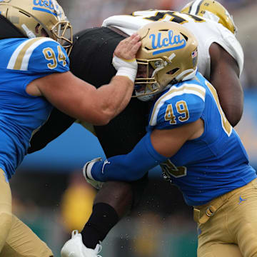 Sep 10, 2022; Pasadena, California, USA; UCLA Bruins defensive lineman Dovid Magna (94) and linebacker Carson Schwesinger (49) tackle Alabama State Hornets running back Marcus II Harris (26) in the second half at Rose Bowl. Mandatory Credit: Kirby Lee-Imagn Images