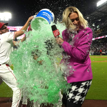 Aug 31, 2024; Anaheim, California, USA;  Los Angeles Angels center fielder Mickey Moniak (16) is doused by first baseman Nolan Schanuel (18) and second baseman Michael Stefanic (38) after hitting a walk-off home run against the Seattle Mariners as Bally Sports reporter Erica Weston watches at Angel Stadium. Mandatory Credit: Kirby Lee-USA TODAY Sports