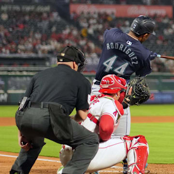 Seattle Mariners center fielder Julio Rodriguez (44) hits a two-RBI single in the fourth inning as Los Angeles Angels catcher Logan O'Hoppe (14) and  home plate umpire Jansen Visconti watch at Angel Stadium on Aug. 31.