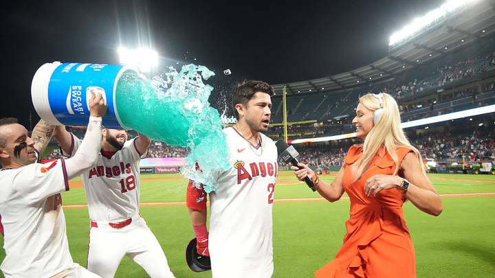 Jul 11, 2025; Anaheim, California, USA; Los Angeles Angels catcher Travis d'Arnaud (25) is doused by teammates shortstop Zach Neto (9) and catcher Logan O'Hoppe (14) during an interview  with Friday Night Baseball on Apple TV  broadcaster Tricia Whitaker after the game against the Arizona Diamondbacks at Angel Stadium. Mandatory Credit: Kirby Lee-Imagn Images