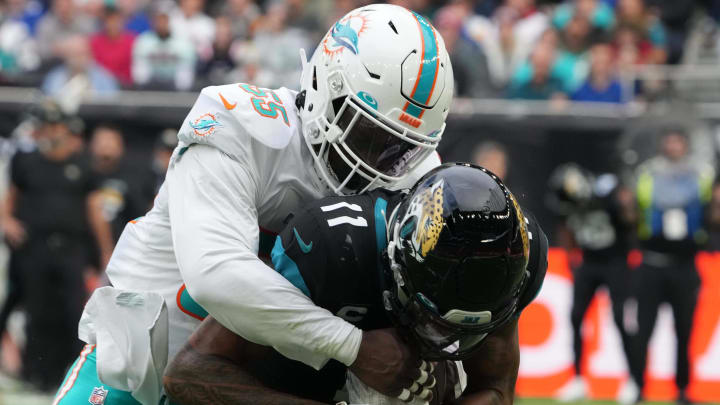 Oct 17, 2021; London, England, United Kingdom; Miami Dolphins outside linebacker Jerome Baker (55) tackles Jacksonville Jaguars wide receiver Marvin Jones (11) in the first half during an NFL International Series game at Tottenham Hotspur Stadium. The Jaguars defeated the Dolphins 23-20. Mandatory Credit: Kirby Lee-USA TODAY Sports