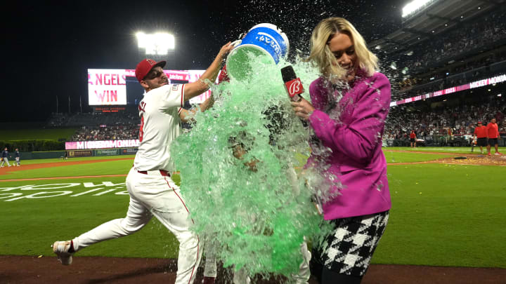 Aug 31, 2024; Anaheim, California, USA;  Los Angeles Angels center fielder Mickey Moniak (16) is doused by first baseman Nolan Schanuel (18) and second baseman Michael Stefanic (38) after hitting a walk-off home run against the Seattle Mariners as Bally Sports reporter Erica Weston watches at Angel Stadium. Mandatory Credit: Kirby Lee-USA TODAY Sports