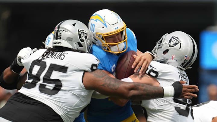 Sep 8, 2024; Inglewood, California, USA; Los Angeles Chargers quarterback Justin Herbert (10) is tackled by Las Vegas Raiders defensive tackle John Jenkins (95) and defensive end Maxx Crosby (98) in the first half at SoFi Stadium. Mandatory Credit: Kirby Lee-Imagn Images