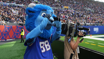 Buffalo Bills mascot Billy Buffalo interacts with WHAM TV camera person Jenna Cottrell during an NFL International Series game at Tottenham Hotspur Stadium.