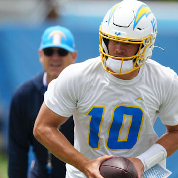 Los Angeles Chargers quarterback Justin Herbert (10) hands the ball off as coach Jim Harbaugh watches during organized team activities at the Hoag Performance Center. 