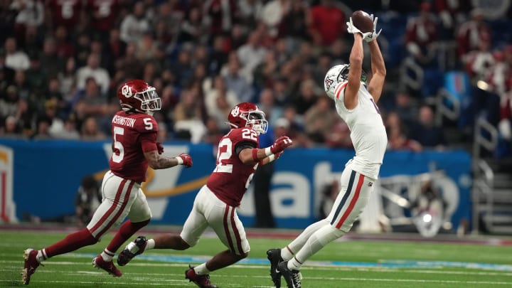 Dec 28, 2023; San Antonio, TX, USA; Arizona Wildcats wide receiver Tetairoa McMillan (4) catches the ball against Oklahoma Sooners defensive back Woodi Washington (5) and defensive back Peyton Bowen (22) in the fist half of the Alamo Bowl at Alamodome. 