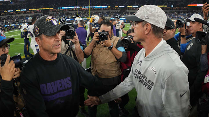 Baltimore Ravens coach John Harbaugh shakes hands with brother and Los Angeles Chargers coach Jim Harbaugh.
