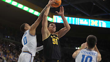 Jan 7, 2025; Los Angeles, California, USA; Michigan Wolverines center Vladislav Goldin (50) shoots the ball against UCLA Bruins guard Kobe Johnson (0) and guard Lazar Stefanovic (10) in the first half at Pauley Pavilion presented by Wescom. Mandatory Credit: Kirby Lee-Imagn Images