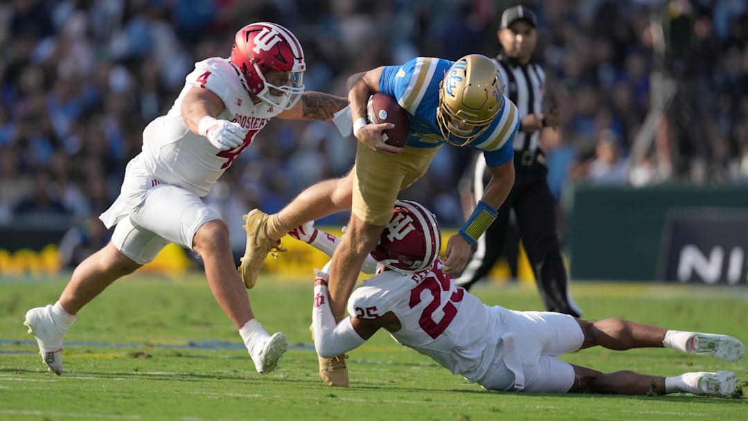 Sep 14, 2024; Pasadena, California, USA; UCLA Bruins quarterback Ethan Garbers (4) is tackled by Indiana Hoosiers linebacker Aiden Fisher (4) and defensive back Amare Ferrell (25) in the first half at Rose Bowl. Mandatory Credit: Kirby Lee-Imagn Images