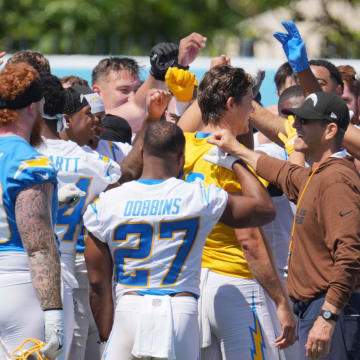 Jun 13, 2024; Costa Mesa, CA, USA; Los Angeles Chargers coach Jim Harbaugh joins hands in a huddle with tight end Donald Parham Jr. (89), running back J.K. Dobbins (27), quarterback Justin Herbert (10) and receiver Ladd McConkey (15) during minicamp at the Hoag Performance Center. Mandatory Credit: Kirby Lee-USA TODAY Sports