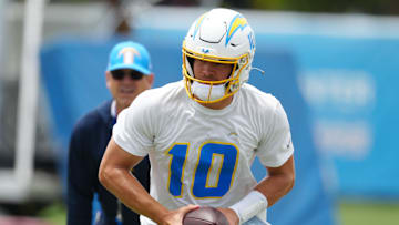 Los Angeles Chargers quarterback Justin Herbert (10) hands the ball off as coach Jim Harbaugh watches during organized team activities at the Hoag Performance Center. Mandatory Credit: Kirby Lee-USA TODAY Sports